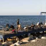 Su un pontile della spiaggia, a una manciata di metri dalle onde che si infrangono sulla battigia, avvistiamo un altro piccolo raduno di praticanti